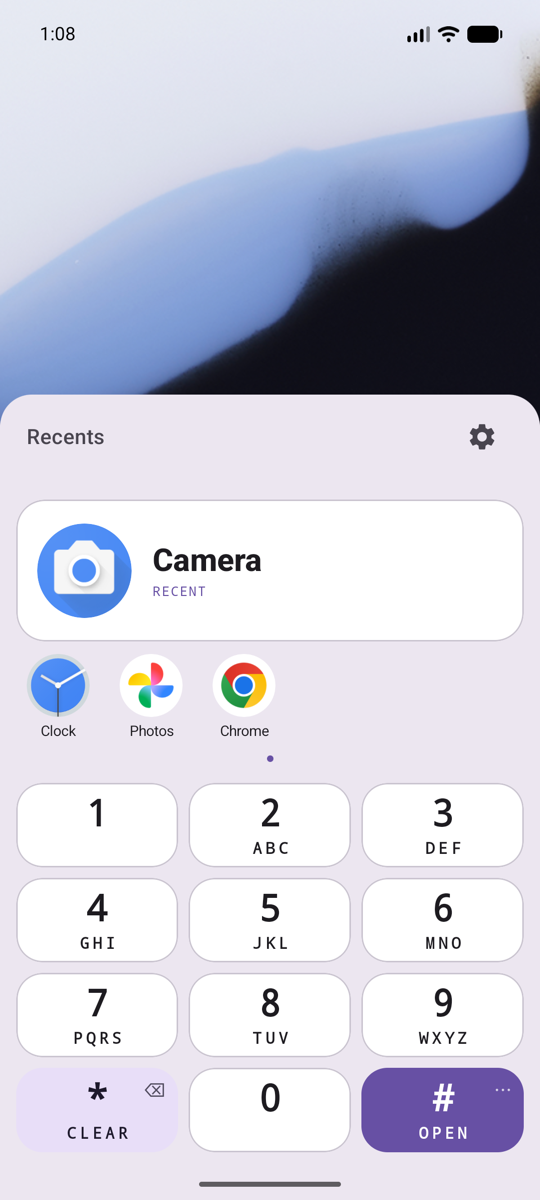 Tapfind over the wallpaper, with nothing typed. The Recents show Camera first, then Clock, Photos and a browser, above the keypad.